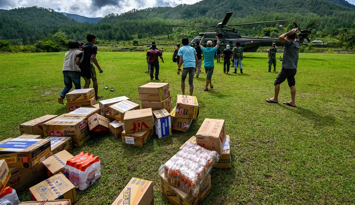 BNPB juga telah mengerahkan empat helikopter untuk mendistribusikan bantuan ke empat kabupaten tersebut. Tampak dalam foto, warga membawa bantuan yang didistribusikan oleh personel TNI AU di wilayah terdampak banjir di Kabupaten Bener Meriah, Provinsi Aceh, pada Kamis 4 Desember 2025. (CHAIDEER MAHYUDDIN/AFP)