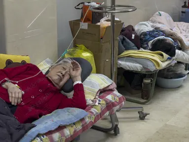 Pasien lanjut usia (lansia) beristirahat di sepanjang koridor bangsal darurat saat mereka menerima infus di Beijing, Kamis (5/1/2023). Pasien, kebanyakan dari mereka lansia, berbaring di tandu di lorong dan menerima oksigen sambil duduk di kursi roda saat kasus COVID-19 melonjak di ibu kota China, Beijing. (AP Photo/Andy Wong)