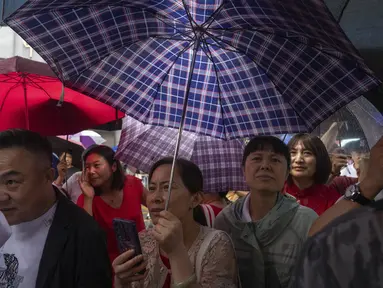 Kerabat dan guru siswa yang mengikuti ujian masuk perguruan tinggi nasional tahunan yang juga dikenal sebagai "Gaokao" menunggu sesi pagi selesai saat hujan turun di Beijing, China, Jumat (7/6/2024). (AP Photo/Ng Han Guan)