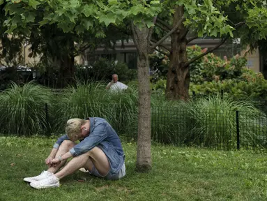 Seorang pria duduk di tempat teduh saat siang hari yang panas di Washington Square Park di New York City (17/7/2019). Panas terik bergerak ke daerah Kota New York, dengan suhu yang diperkirakan akan mencapai 100 derajat pada akhir pekan ini. (AFP Photo/Drew Angerer)