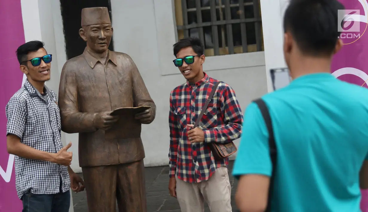 Pengunjung berfoto patung Presiden pertama RI Sukarno dengan pose membacakan naskah Proklamasi di kawasan Kota Tua, Jakarta, Rabu (15/11). Patung karya seniman Dolorosa Sinaga itu dibuat dengan bahan Resin. (Liputan6.com/Immanuel Antonius)