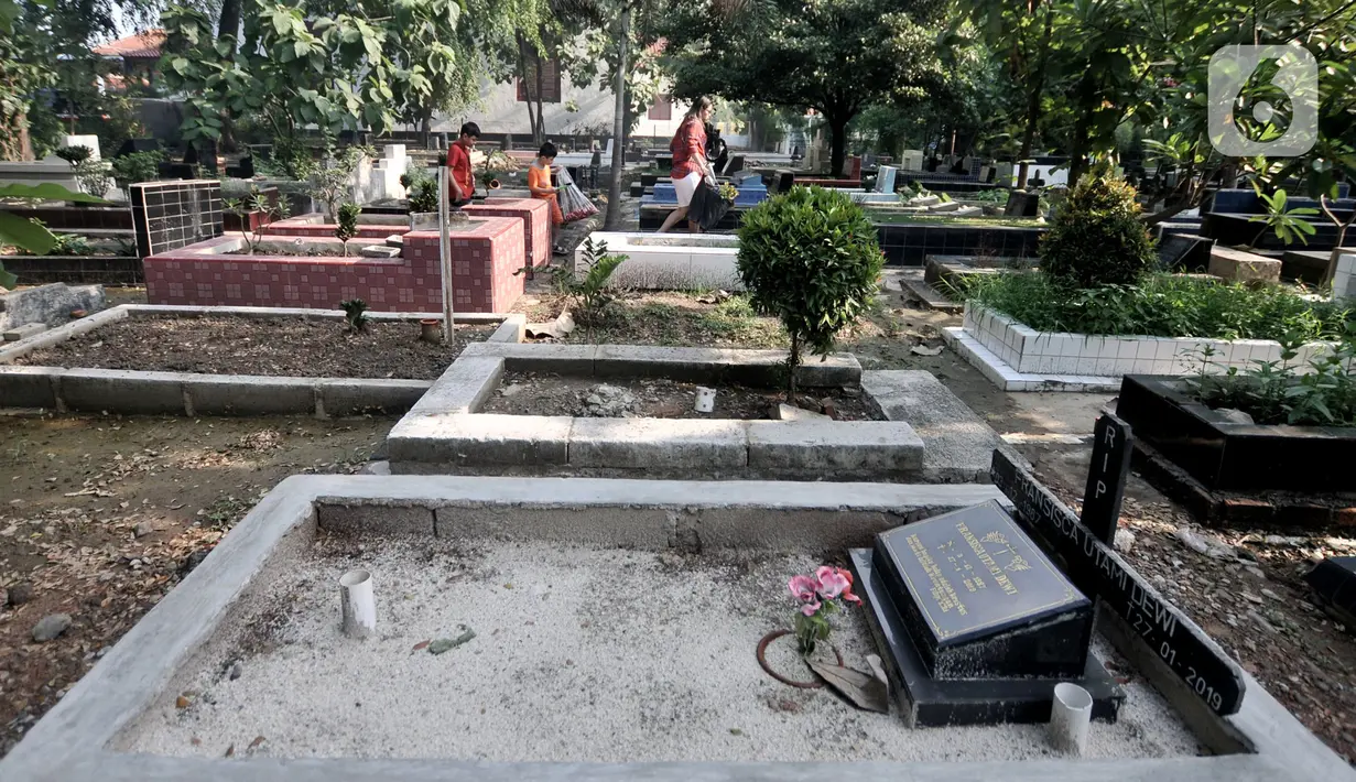 Keluarga membawa bunga saat saat ziarah di kompleks pemakaman Gereja Tugu, Semper, Jakarta, Senin (23/12/2019). Ziarah menjadi tradisi keluarga keturunan Portugis di Kampung Tugu menjelang Hari Raya Natal. (merdeka.com/Iqbal Nugroho)