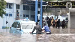 Sopir mendorong taksi untuk dipindahkan ke tempat lebih tinggi di Pool Blue Bird, Kramat Jati, Jakarta Timur, Rabu (1/1/2020). Banjir yang terjadi akibat hujan deras yang mengguyur Jakarta dan sekitarnya menyebabkan puluhan taksi dan belasan mobil terendam. (merdeka.com/Iqbal S. Nugroho)