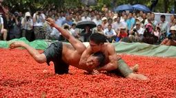 Petarung bergulat diatas tumpukan tomat selama mengikuti festival lokal budaya dan pariwisata di Tianyang , Guangxi Zhuang Autonomous Region , Cina , 14 April 2016. (REUTERS / Stringer)