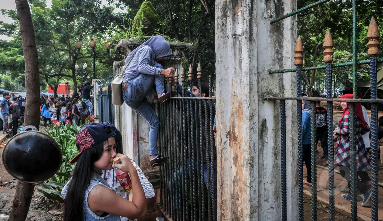 Tampak seorang perempuan nekat memanjat pagar di kawasan Monas, Jakarta, Minggu (19/4/2015). Aksi nekat warga ini ditengarai oleh petugas yang menutup akses masuk pengunjung Monas. (Liputan6.com/Faizal Fanani)