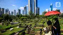 Warga melintas di antara makam di TPU Karet Bivak, Jakarta, Selasa (11/5/2021). Pemprov DKI akan memberlakukan larangan ziarah kubur Idulfitri di seluruh TPU mulai 12 hingga 16 Mei untuk mencegah terjadinya penyebaran Covid-19 saat berkumpul untuk berziarah. (Liputan6.com/JohanTallo)