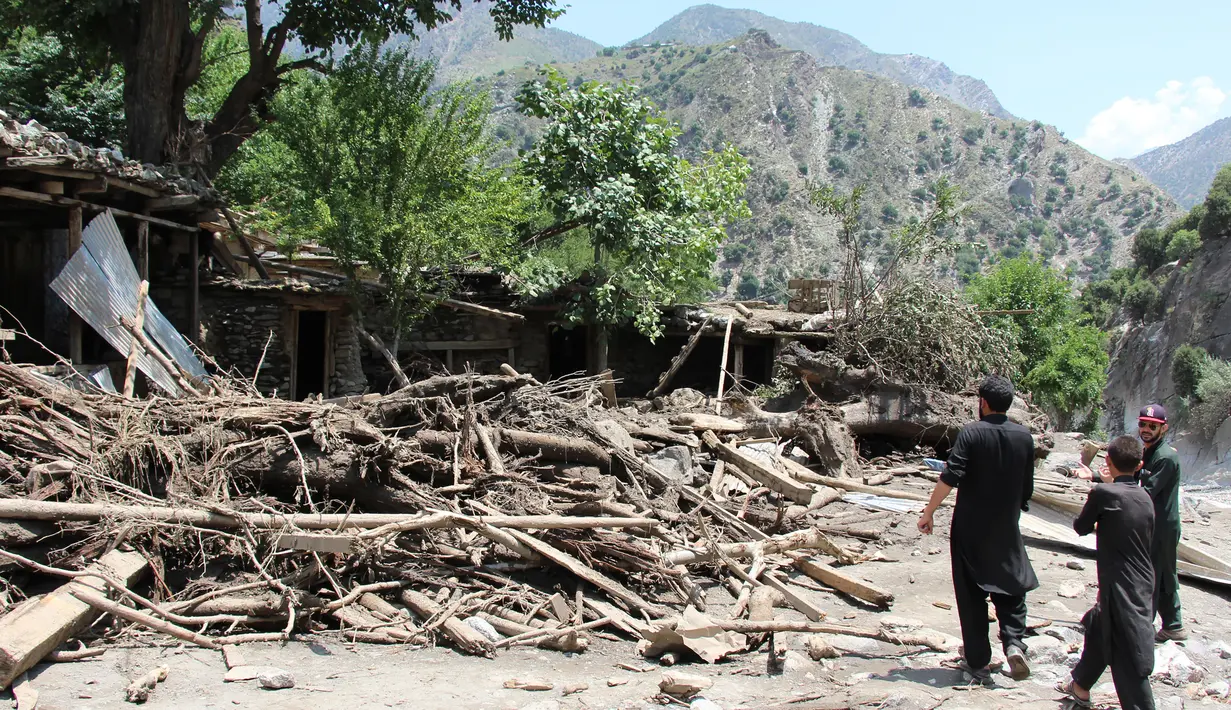 Warga mengamati bangunan rumah yang rusak akibat dihantam banjir bandang di Ursoon, daerah terpencil Chitral di Pakistan utara, Minggu (3/7). Banjir bandang akibat hujan lebat yang lama itu telah menewaskan sedikitnya 43 orang. (GUL HAMAAD Farooqi/AFP)
