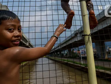 Anak-anak bermain dan berenang di aliran Kalimalang, Jakarta, Sabtu (15/2/2020). Cuaca yang tidak menentu membuat aliran air terkadang menjadi deras sehingga akan membahayakan keselamatan anak-anak saat bermain dan berenang. (merdeka.com/Imam Buhori)