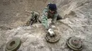 Pencari ranjau dari Kementerian Dalam Negeri Ukraina mengumpulkan bahan peledak pada sebuah lubang untuk meledakkannya dekat ladang ranjau di Desa Moshchun, dekat Kiev, Ukraina, 19 April 2022. (AP Photo/Efrem Lukatsky)
