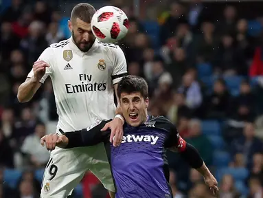 Pemain Real Madrid, Karim Benzema melakukan sundulan saat berebut bola dengan pemain Leganes, Unai Bustinza pada laga leg pertama babak 16 besar Copa del Rey di Santiago Bernabeu, Rabu (9/1). Madrid sukses mengandaskan Leganes 3-0. (AP/Manu Fernandez)