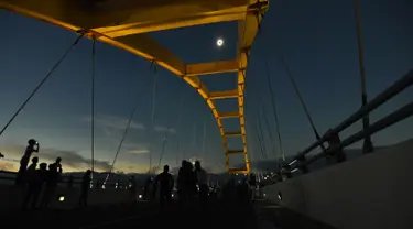 Warga menyaksikan fase puncak Gerhana Matahari Total (GMT) yang dilihat dari Jembatan Teluk Palu, Sulawesi Tengah, Rabu (9/3/2015). (Nanang/AFP)