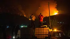 Orang-orang menunggu di atas truk air saat kebakaran hutan berkobar di Gunung Pirque, El Hoyo, wilayah Patagonia provinsi Chubut, Argentina pada 7 Januari 2026. Ribuan hektar hutan di Gunung Pirque, El Hoyo, wilayah Patagonia provinsi Chubut, Argentina, hancur akibat kebakaran yang terjadi sejak 6 Januari 2026. (Martin LEVICOY/AFP)