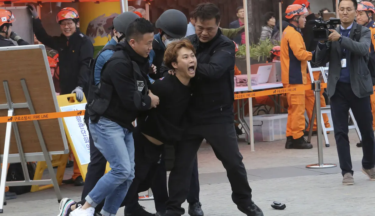 Seorang teroris tiruan ditangkap oleh petugas polisi selama latihan anti-terorisme di stasiun kereta bawah tanah Shindorim di Seoul, Korea Selatan, Selasa (29/10/2019). Latihan anti-terorisme bulan ini dikombinasikan dengan latihan pencegahan bencana. (AP Photo/Ahn Young-joon)