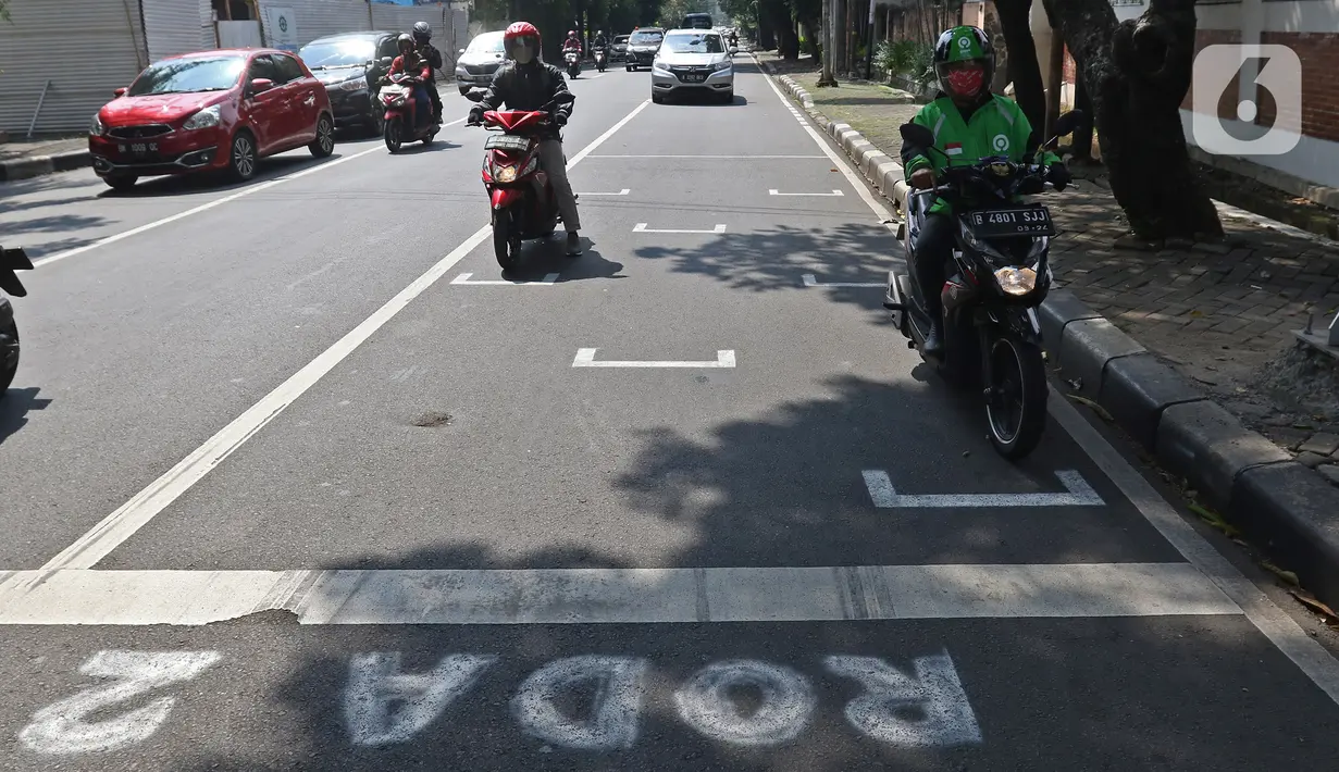 Pembatas Jarak Bagi Pengendara Motor: Pengendara motor berhenti pada garis pembatas antarpengendara di kawasan Hang Tuah Raya, Jakarta, Selasa (16/6/2020). Garis itu untuk membatasi jarak antarpengendara guna mencegah penyebaran COVID-19. (Liputan6.com/Herman Zakharia)