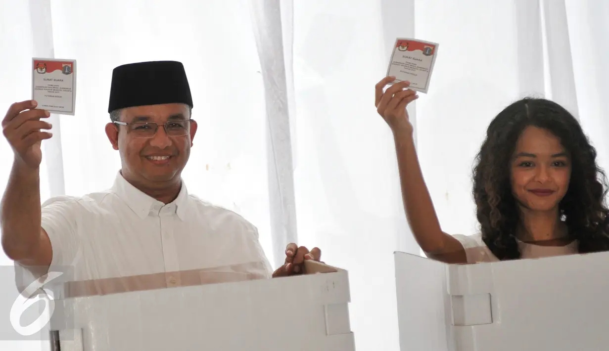 Anies Baswedan bersama anaknya menunjukan kertas suara sebelum memasukan ke kotak saat menggunakan hak pilihnya di TPS 28 Cilandak, Jakarta Selatan, Rabu (19/4). (Liputan6.com/Yoppy Renato)