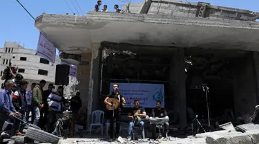 Seorang penyanyi Palestina tampil selama acara musik di puing-puing bangunan yang baru-baru ini hancur oleh serangan udara Israel di kota Gaza, Selasa (14/5/2019). Aksi tersebut untuk menyerukan pemboikotan terhadap Kontes Lagu Eurovision 2019 yang diselenggarakan di Israel. (REUTERS/Mohammed Salem)