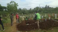 Petugas tengah menggali makam untuk tiga korban pembunuhan sadis Pulomas. (Liputan6.com/M. Radityo P)
