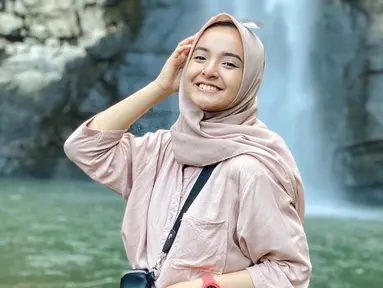 Nabila Ishma berusaha untuk terus tersenyum lebar seperti janjinya ke Eril. Nabila memiliki senyum yang sangat manis. Terlebih saat tersenyum ketika ia jalan-jalan destinasi wisata air terjun. Senyum manisnya ini banjir like dari netizen. (Liputan6.com/IG/@nabilaishma)