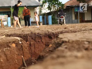 Warga mengamati tanah terbelah di lapangan RT 02 RW 02 Kampung Pedurenan, Kelurahan Cisalak Pasar, Cimanggis, Depok, Jawa Barat, Senin (22/10). Tanah tersebut terbelah sepanjang 20 meter dengan kedalaman 1,5 meter. (Liputan6.com/Immanuel Antonius)