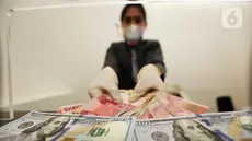 Karyawan menunjukkan uang rupiah dan dolar AS di Jakarta, Rabu (30/12/2020). Nilai tukar rupiah di pasar spot ditutup menguat 80 poin atau 0,57 persen ke level Rp 14.050 per dolar AS. (Liputan6.com/Johan Tallo)