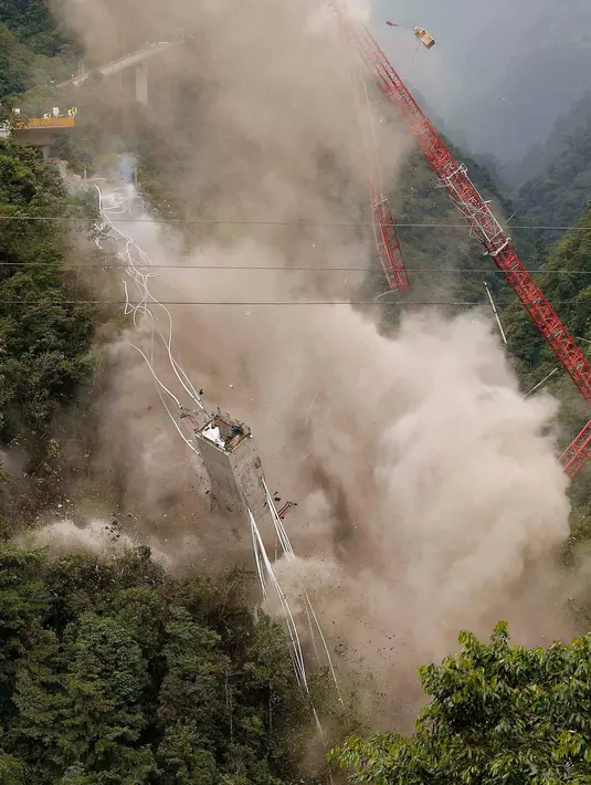 Momen saat peruntuhan sebuah jembatan gantung oleh para insinyur di Chirajara, Kolombia, Rabu (11/7). Sebelumnya, sebagian jembatan runtuh dan menewaskan sembilan pekerja saat pembangunannya pada Januari lalu. (AP Photo/Fernando Vergara)