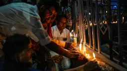 Orang-orang menyalakan lilin untuk memberi penghormatan kepada para korban ambruknya jembatan di New Delhi, India, Senin (31/10/2022). Jembatan gantung tersebut ambruk pada 31 Oktober 2022 malam, yang menyebabkan ratusan orang jatuh ke sungai. (AP Photo/Rafiq Maqbool)