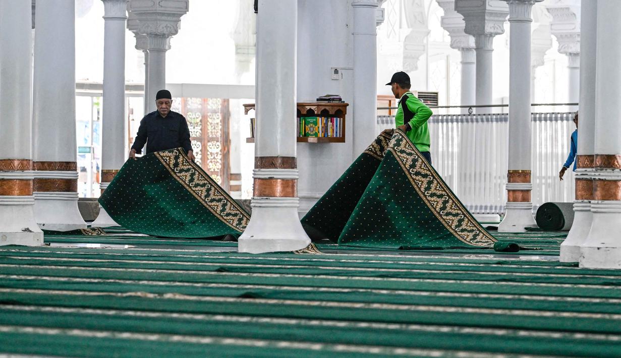 Seperti diketahui, Pemerintah melalui Sidang Isbat yang dilaksanakan Kementerian Agama telah menetapkan awal puasa 1 Ramadan 1447 Hijriah jatuh pada Kamis 19 Februari 2026. Tampak dalam foto, para pekerja menyiapkan karpet untuk salat tarawih pertama pada bulan suci Ramadan 1447 Hijriah di Masjid Agung Baiturrahman, Banda Aceh, Rabu 18 Februari 2026. (CHAIDEER MAHYUDDIN/AFP)