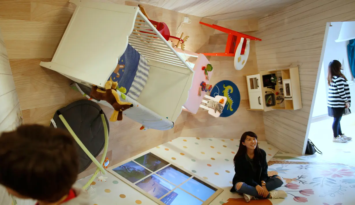 Pengunjung berpose di lantai rumah terbalik di Huashan Creative Park, Taipei, Taiwan, (7/4). Sekelompok arsitek Taiwan membangun rumah seluas 300 meter yang menghabiskan dana US$ 600.000 dalam kurun waktu 2 bulan. (REUTERS/Tyrone Siu)