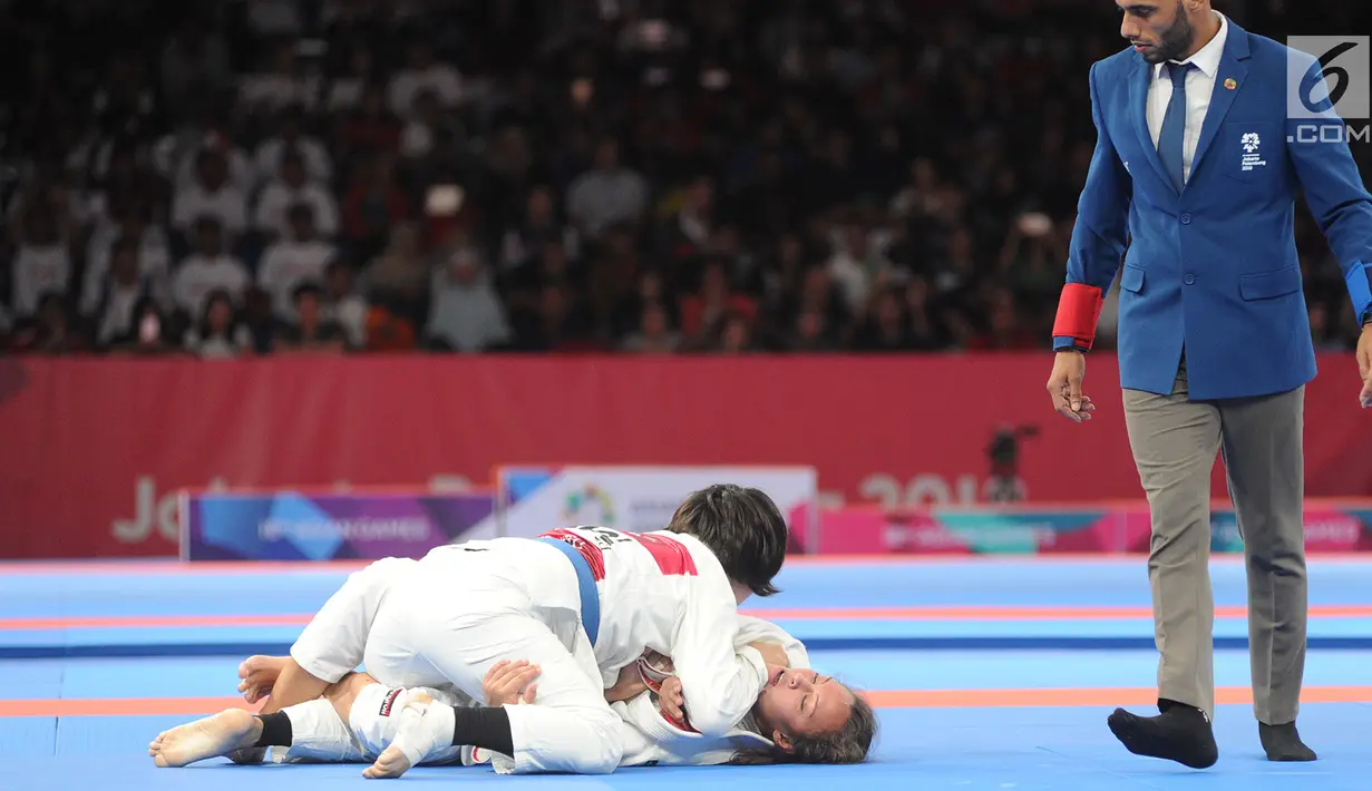 Atlet Jujitsu putri Mongolia Tsogkhuu Udval mengunci Simone Julia dari Indonesia saat bertanding pada nomor final putri 62 kg Asian Games 2018, Jakarta, Sabtu (25/8). Simone gagal mempersembahkan medali perunggu. (Merdeka.com/Arie Basuki)
