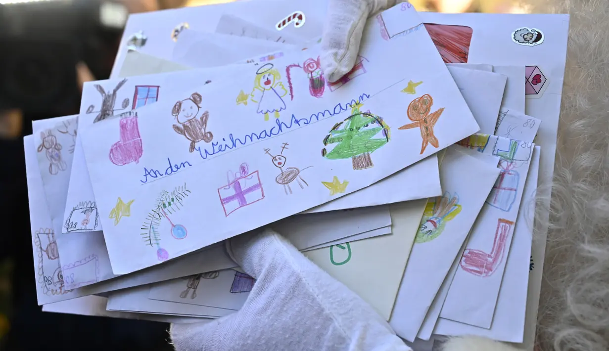 Seorang pria sebagai Father Christmas memegang surat daftar harapan anak-anak saat pembukaan kantor pos Sinterklas di Himmelpfort, Jerman, Kamis (14/11/2019). Setiap tahunnya ada sekitar ratusan ribu surat yang masuk dari 64 negara yang harus dijawab Santa. (Tobias SCHWARZ / AFP)