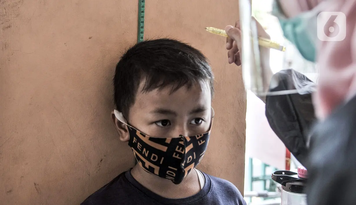 Petugas paramedis mengukur tinggi salah seorang anak sebelum mengikuti program BIAS di Kantor Kelurahan Tamansari, Jakarta, Selasa (24/11/2020). Selama masa pandemi, pemerintah melalui Dinas Kesehatan tetap menggelar Bulan Imunisasi Anak Sekolah (BIAS). (merdeka.com/Iqbal S. Nugroho)