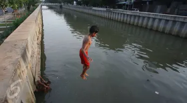 Seorang anak melompat ke anak Kali Ciliwung di Jakarta, Rabu (13/7). Bersihnya kali yang berada di Ibu Kota itu dimanfaatkan anak-anak sekitar untuk berenang sambil mengisi waktu libur sekolah. (Liputan6.com/Immanuel Antonius)