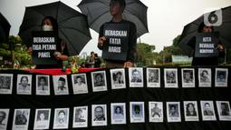 Anggota Jaringan Solidaritas Korban untuk Keadilan (JSKK) membawa poster bertuliskan "Bebaskan Tiga Petani Pakel", "Bebaskan Fatia Haris", dan "Kita Berhak Kritis!" saat melakukan Aksi Kamisan ke-795 di seberang Istana Merdeka, Jakarta, Kamis (16/11/2023). (Liputan6.com/Faizal Fanani)