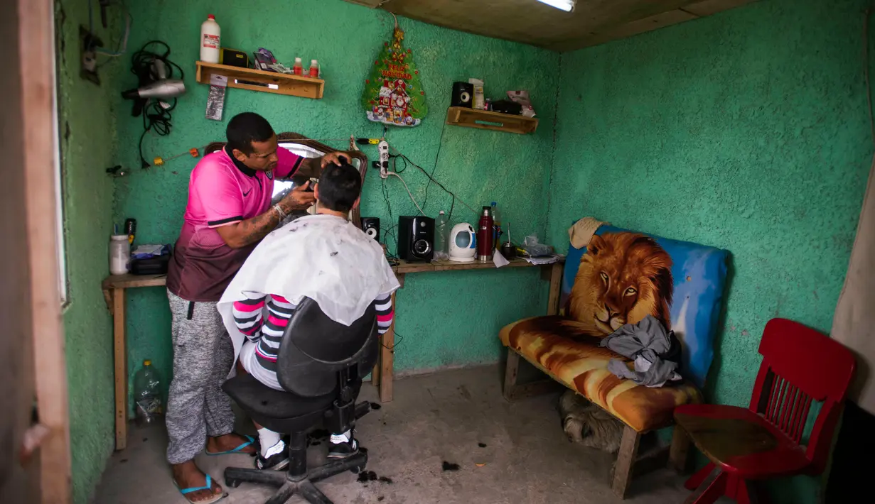 Seorang narapidana mencukur rambut narapidana lainnya di salah satu pangkas rambut yang berada di Penjara Punta de Rieles, Montevideo, Uruguay, 9 Mei 2019. Narapidana harus memiliki minimal enam bulan perilaku baik untuk bisa berbisnis di Penjara Punta de Rieles. (AP Photo/Matilde Campodonico)