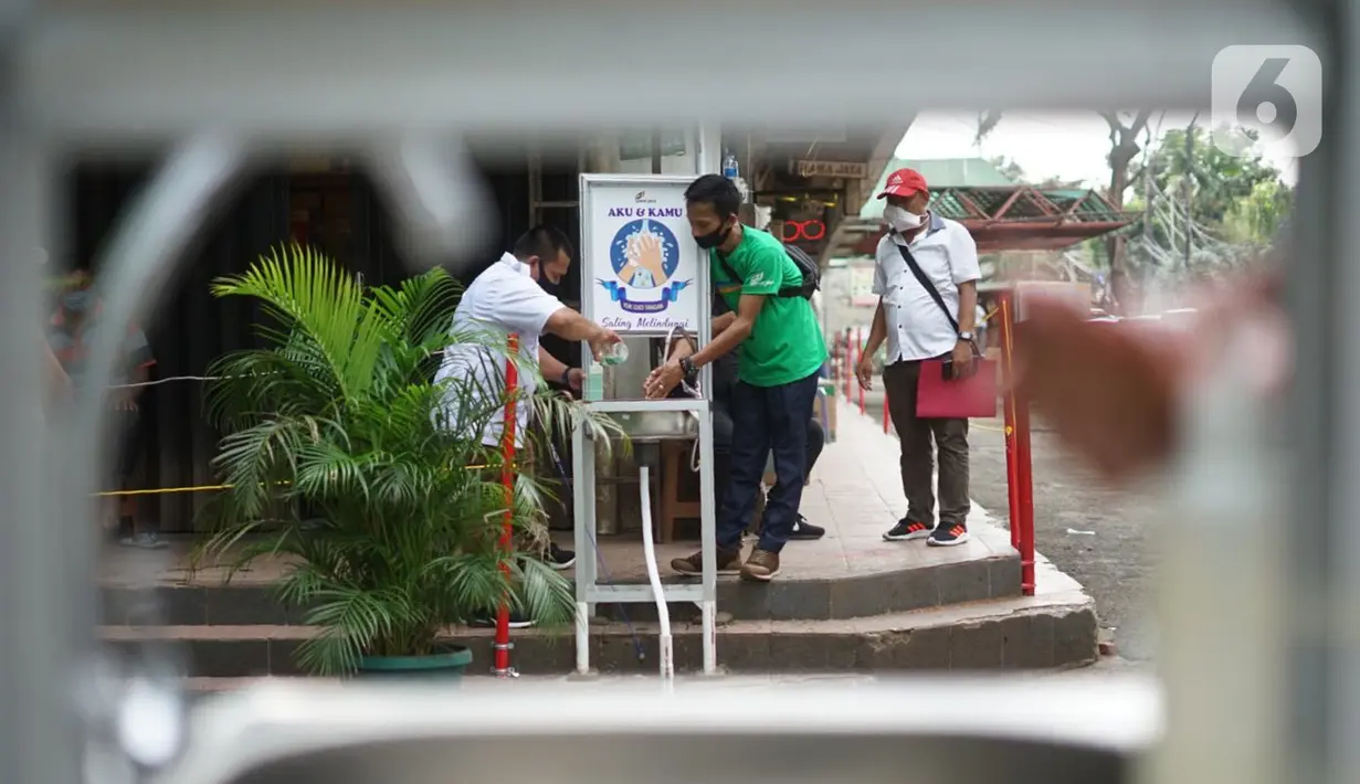 Pengunjung mencuci tangan saat masuk ke kawasan Pasar Minggu, Jakarta, Selasa (23/6/2020). Pascapenutupan tiga hari terkait ditemukannya tiga pedagang yang positif COVID-19, pengunjung Pasar Minggu kini diwajibkan mencuci tangan dan cek suhu tubuh. (Liputan6.com/Immanuel Antonius)