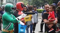 Seperhero menyapa warga saat melakukan aksi teaterikal di Bundaran HI, Jakarta, Minggu (16/4). Dalam aksi teaterikal tersebut para superhero menyuarakan untuk terus mendukung KPK. (Liputan6.com/Angga Yuniar)
