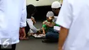 Seorang anak bersama orang tuanya makan siang sebelum memulai aksi di Medan Merdeka Timur, Jakarta, Jumat (4/11). Massa melakukan aksi di depan Istana Negara menuntut penegakan hukum kasus dugaan penistaan agama. (Liputan6.com/Faizal Fanani)
