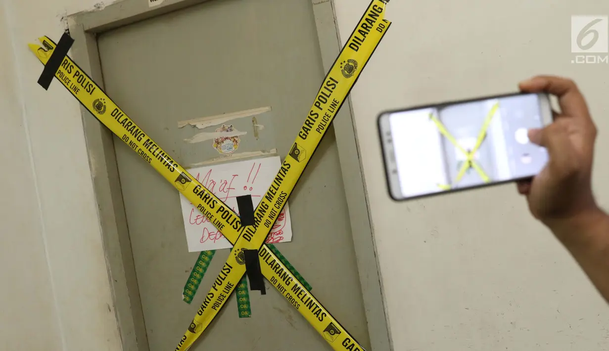 Salah satu pintu Kantor PT Liga Indonesia di Kawasan Kuningan dipasangi garis pembatas, Jakarta, Jumat (1/2). Satgas Anti Mafia Bola melakukan penggeledahan PT Liga Indonesia terkait dugaan pengaturan hasil pertandingan. (Liputan6.com/Helmi Fithriansyah)