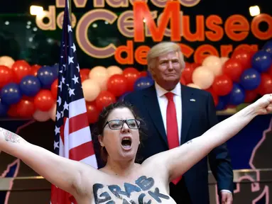 Aktivis Femen dengan kondisi telanjang dada berdiri di depan patung lilin Donald Trump di Museum Wax, Madrid, Spanyol, Selasa (17/1). (AFP PHOTO/GERARD JULIEN)
