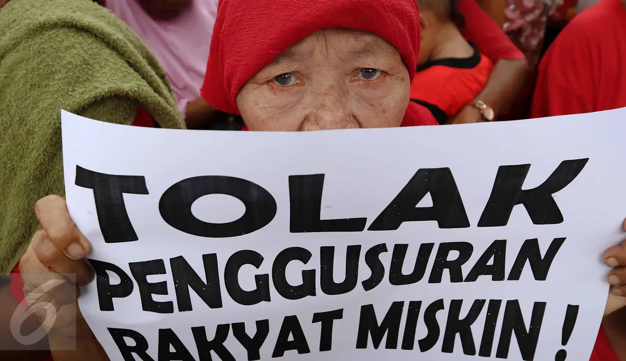 Seorang ibu memperlihatkan poster berisi tuntutan saat menggelar unjuk rasa di depan Balai Kota DKI Jakarta, Kamis (3/11). Dalam aksinya, mereka menolak penggusuran terhadap rakyat miskin dan menuntut penurunan harga sembako. (Liputan6.com/Faizal Fanani)