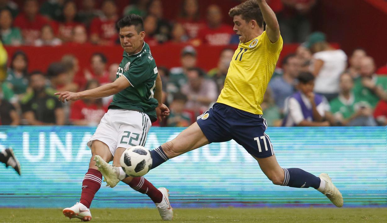 Aksi pemain Meksiko, Hirving Lozano (kiri) melepaskan tembakan melewati pemain Skotlandia, Ryan Christie pada laga uji coba di Azteca Stadium, Meksiko City, (2/6/2018). Meksiko menang 1-0. (AP/Rebecca Blackwell)