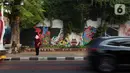Seorang warga beridir di depan lukisan mural dari tangan PPSU yang memanfaatkan tanaman merambat hijau. (Liputan6.com/Johan Tallo)