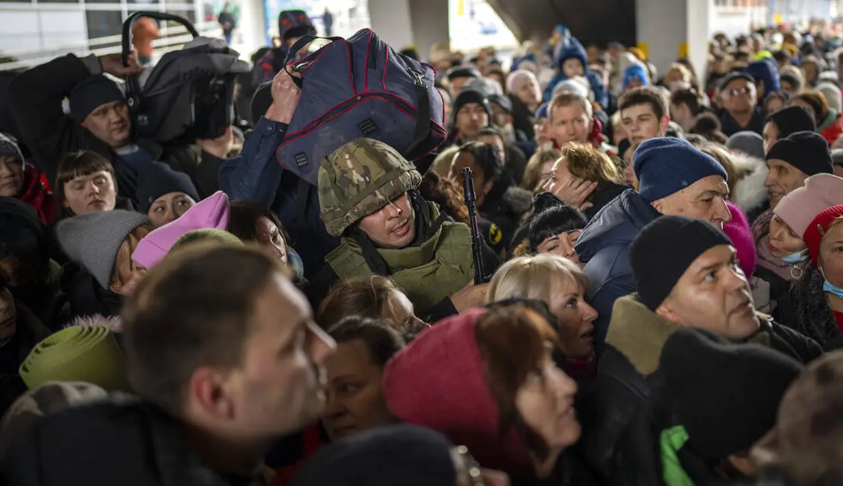 Seorang tentara Ukraina mencoba membubarkan kerumunan saat mereka mendorong untuk memasuki kereta api ke Lviv di Stasiun Kiev, Ukraina, 4 Maret 2022. (AP Photo/Emilio Morenatti)