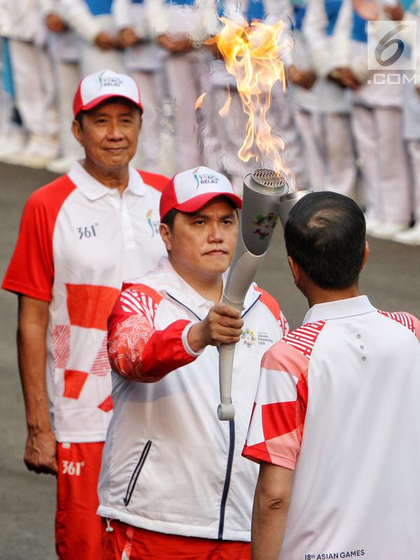 Ketua Inasgoc Erick Thohir saat menyalakan api obor Asian Games 2018 ke Presiden Joko Widodo sebelum upacara penurunan Bendera Merah Putih di Istana Negara Jakarta, Jumat (17/8). (Liputan6.com/Pool/Eko)