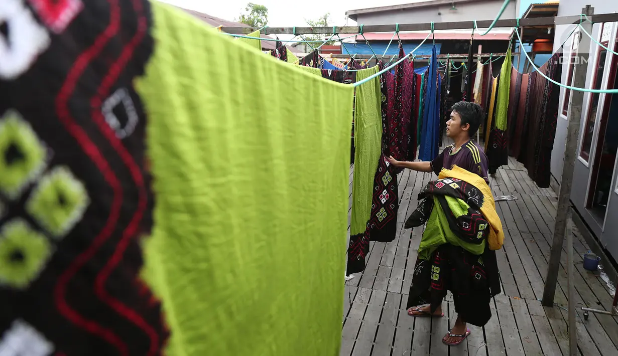 Pekerja mengangkat kain sasirangan yang telah dijemuri di kawasan Banjarmasin, Kalimantan Selatan, Senin (26/3). Kain sasirangan ini diwariskan secara turun temurun sejak abad XI. (Liputan6.com/Immanuel Antonius)