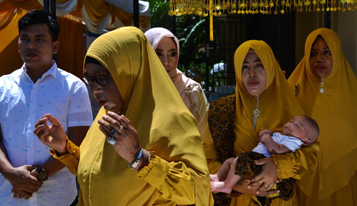 Tokoh adat dan agama menggendong bayi pada ritual 'peutron tanoh aneuk' (turun tanah anak) di Banda Aceh, Aceh, Senin (15/7/2019). Ritual turun tanah anak yang telah menjadi tradisi sakral bagi masyarakat Aceh yang dilaksanakan pada saat bayi berusia 44 hari. (CHAIDEER MAHYUDDIN / AFP)