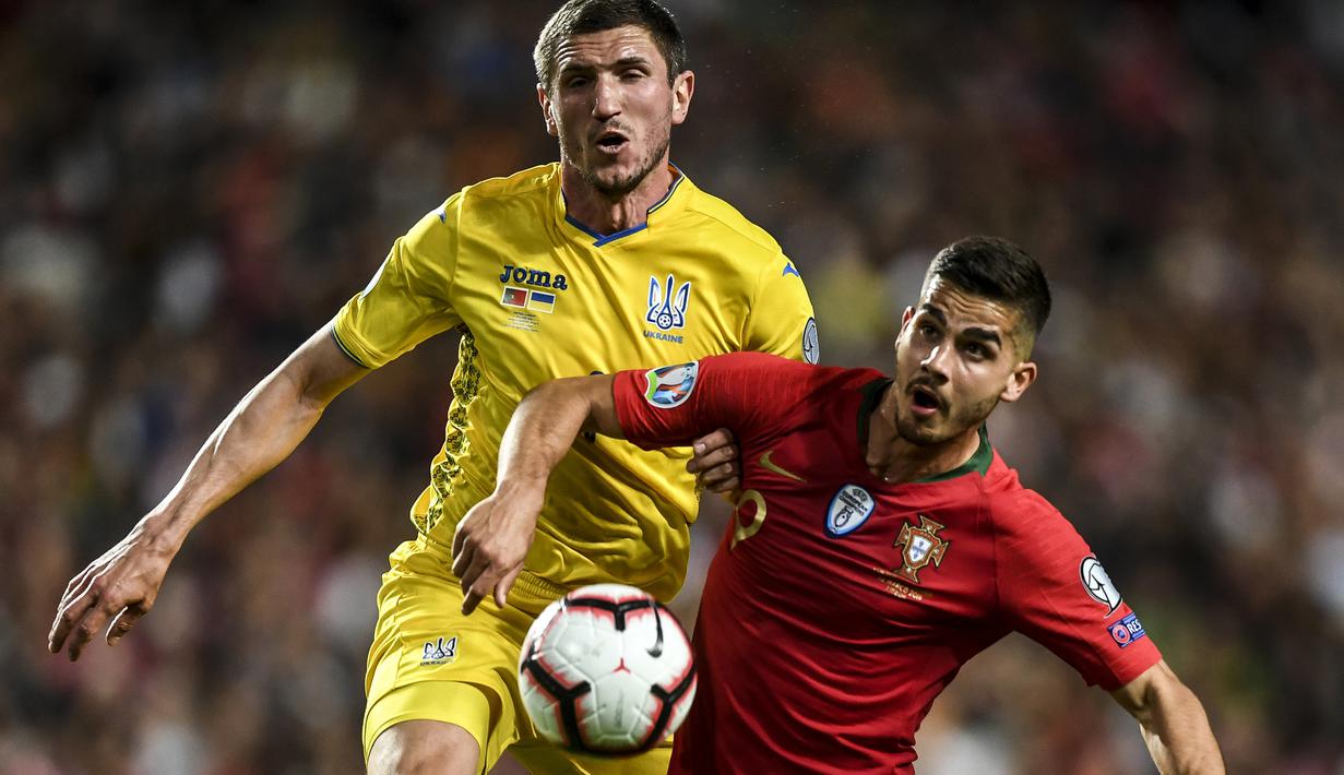 Striker Portugal, Andre Silva, berusaha melewati bek Ukraina, Sergii Kryvtsov, pada laga Kualifikasi Piala Eropa 2020 di Stadion Luz, Lisbon, Jumat (22/3). Kedua negara bermain imbang 0-0. (AFP/Patricia De Melo Moreira)