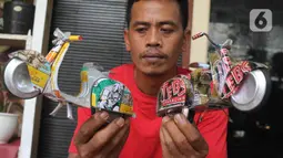 Perajin Ogifson Harianja, menunjukkan miniatur vespa dari kaleng bekas, Jakarta, Jumat (7/1/2022). Pemerintah melalui Kemenko Perekonomian telah mengumumkan bahwa plafon penyaluran KUR 2022 ditingkatkan menjadi Rp373,17 triliun, dengan suku bunga tetap sebesar 6 persen. (Liputan6.com/Angga Yuniar)