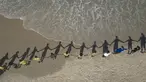 Orang-orang membuat barisan berpegangan tangan di sepanjang pantai Sao Conrado untuk berpelukan secara simbolis dengan laut pada Hari Laut Sedunia di Rio de Janeiro, Brasil, Kamis, 8 Juni 2023. (AP Photo/Bruna Prado)
