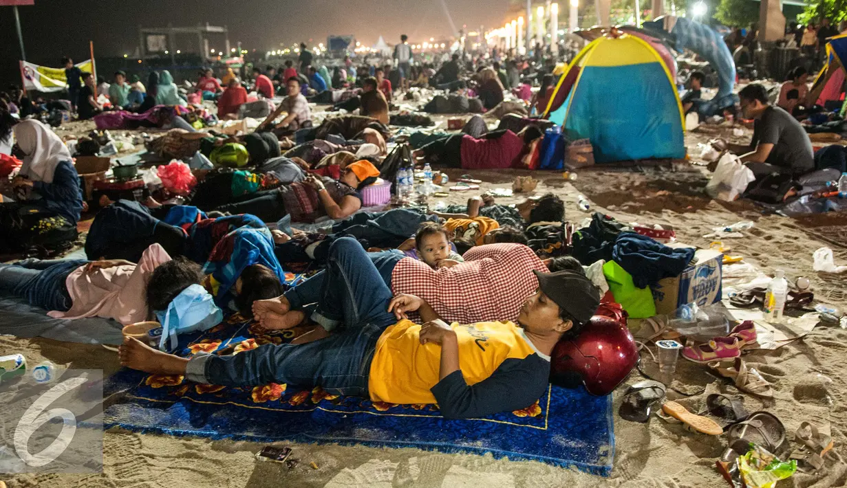 Sejumlah pengunjung tidur menggunakan berbagai macam alas di pinggir pantai usai menyaksikan atraksi kembang api pergantian tahun di Pantai Lagoon , Ancol, Jakarta, Minggu (1/1). (Liputan6.com/Gempur M. Surya)